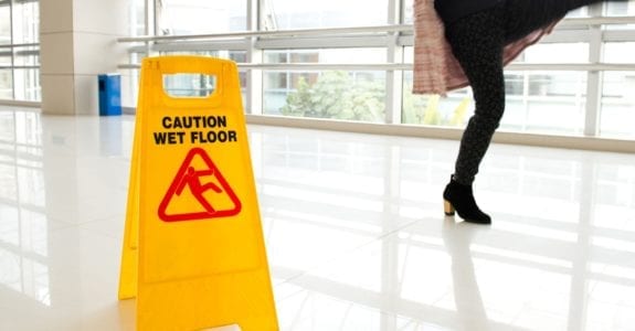 woman slips next to wet floor sign